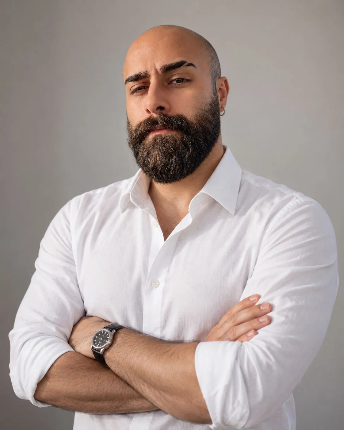 Founder Sedat Üstünova in a white shirt, arms folded, against a grey studio background.